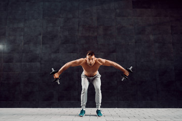 Full length of handsome fit muscular caucasian shirtless blonde bearded man bending forward and...
