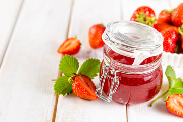 Strawberry jam in glass jar, copy space, white wood background
