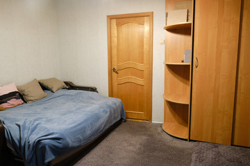 Large made-up bed with pillows, wardrobe and door to the living room