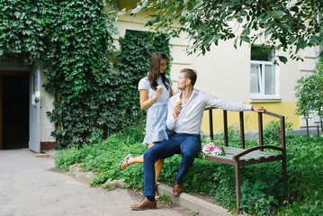 A beautiful couple in love, a guy and a girl sit on a bench and eat ice cream on a summer day