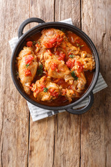 Braised rabbit in tomato sauce with white wine and herbs close-up in a pan. Vertical top view