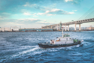 A pilot ship or Tug ship in is guiding a large Cruise ship boat out to the ocean in Yokohama Japan.