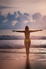 Slender female Silhouette on a background of sea waves and the sky with the setting sun