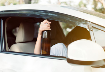 Drunk asian woman drinking alcohol while driving car on road,Women drive her car with a bottle of beer,Dangerous driving concept