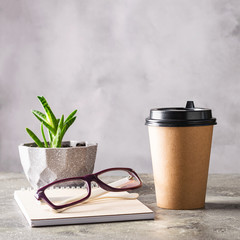 Disposable paper cup with coffee drink or tea notepad glasses on the desktop. Concept business lunch break zero waste.