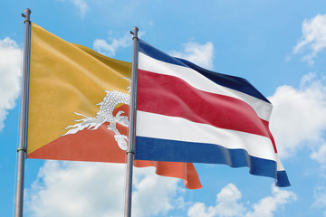 Costa Rica and Bhutan flags waving in the wind against white cloudy blue sky together. Diplomacy concept, international relations.