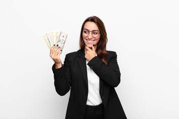 young businesswoman smiling with a happy, confident expression with hand on chin, wondering and...
