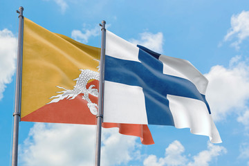 Finland and Bhutan flags waving in the wind against white cloudy blue sky together. Diplomacy concept, international relations.