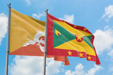 Grenada and Bhutan flags waving in the wind against white cloudy blue sky together. Diplomacy concept, international relations.