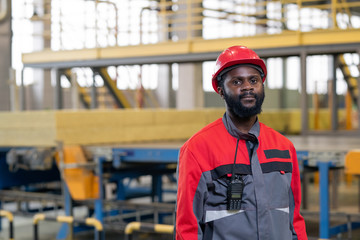 Portrait of serious Black laborer with walkie-talkie device on jacket working at constriction plant