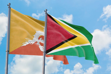 Guyana and Bhutan flags waving in the wind against white cloudy blue sky together. Diplomacy concept, international relations.