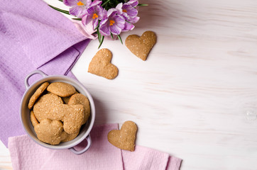 lilac crocuses and sesame dry cookies in the form of heart on a light wooden table