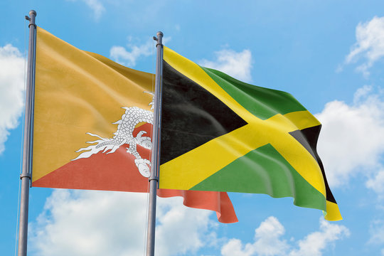 Jamaica and Bhutan flags waving in the wind against white cloudy blue sky together. Diplomacy concept, international relations.