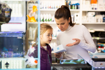 Woman with girl looking for aquarium accessories in store