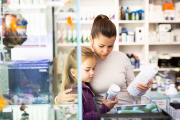 Woman with daughter searching aquarium supplies in shop