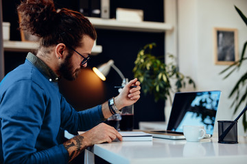 Creative caucasian bearded graphic designer sitting in his office and drawing in notebook.