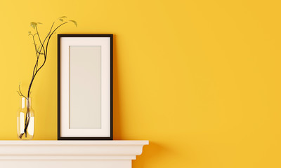 Black blank picture frame on yellow room wall have flower vase placed on the fireplace