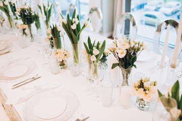 formal luxury elegant wedding decor restaurant tables served white tablecloth, plates, menus, glasses, tulips in vases, orchids, candles silver chairs, blue background