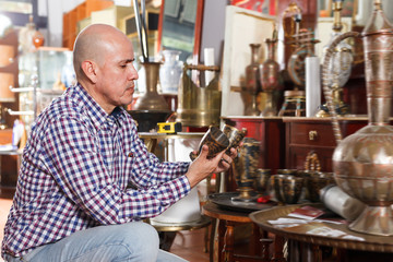 Smiling male carefully examining antiques