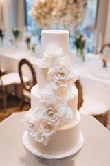 white exquisite luxury three-tier wedding cake with mastic flowers