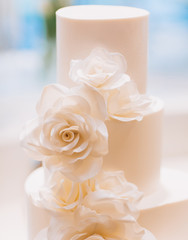 white exquisite luxury three-tier wedding cake with mastic flowers