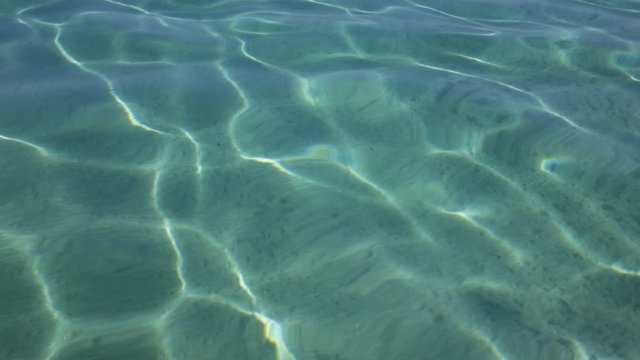 Closeup view of beautiful rippling clean transparent salt water of Aegean sea splashing softly at scenic sandy beach outdoor. Video footage of marine landscape of Greece.