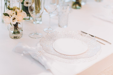 formal luxury elegant wedding decor restaurant tables served white tablecloth, plates, menus, glasses, tulips in vases, orchids, candles silver chairs, blue background