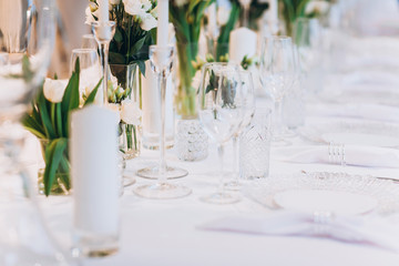 formal luxury elegant wedding decor restaurant tables served white tablecloth, plates, menus, glasses, tulips in vases, orchids, candles silver chairs, blue background