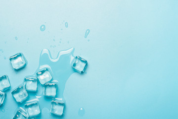 Ice cubes with water on a blue background. Ice concept for drinks. Banner. Flat lay, top view