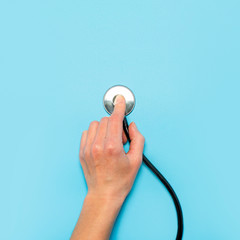 Female hand holds a stethoscope on a blue background. Concept doctor, doctor's appointment, virus,...
