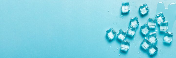 Ice cubes with water on a blue background. Ice concept for drinks. Banner. Flat lay, top view
