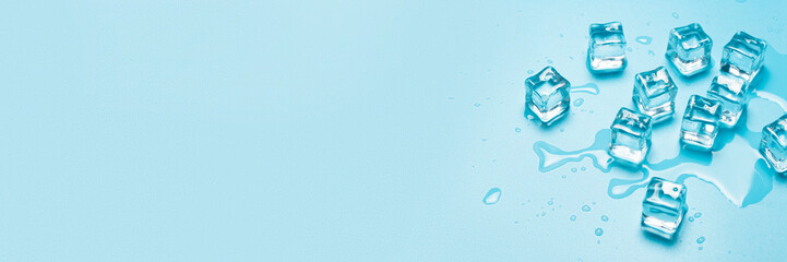 Ice cubes with water on a blue background. Ice concept for drinks. Banner. Flat lay, top view