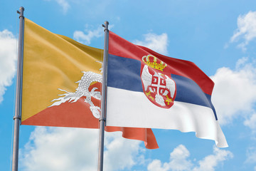 Serbia and Bhutan flags waving in the wind against white cloudy blue sky together. Diplomacy concept, international relations.