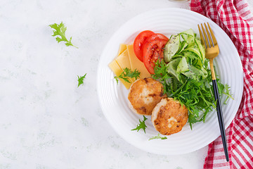 Ketogenic lunch. Chicken burger with tomato, cucumber, cheese and arugula salad without bun. Chicken patties. Healthy food. Keto/paleo diet. Top view, overhead