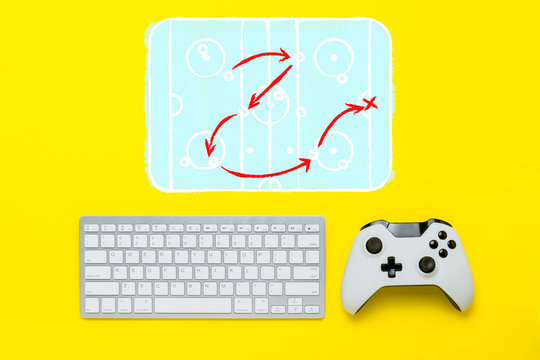 Keyboard and controller on a yellow background. Added drawing hockey rink and tactical scheme. The concept of the game console. Flat lay, top view.