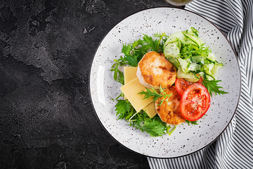 Ketogenic lunch. Chicken burger with tomato, cucumber, cheese and arugula salad without bun. Chicken patties. Healthy food. Keto/paleo diet. Top view, overhead