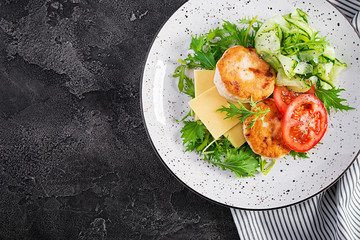 Ketogenic lunch. Chicken burger with tomato, cucumber, cheese and arugula salad without bun. Chicken patties. Healthy food. Keto/paleo diet. Top view, overhead