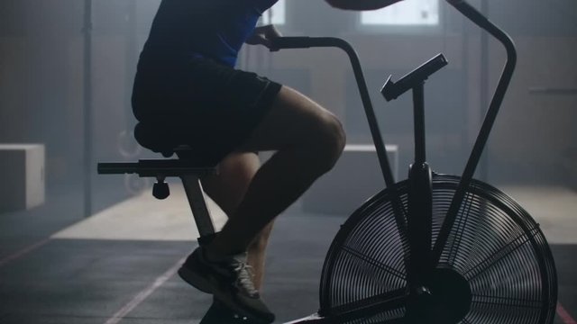 Man doing intense workout on gym bike. Fitness male using air bike for cardio workout at gym