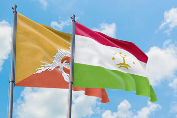 Tajikistan and Bhutan flags waving in the wind against white cloudy blue sky together. Diplomacy concept, international relations.