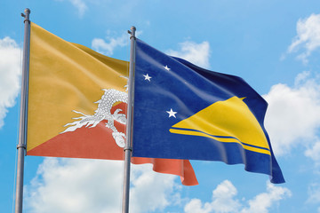 Tokelau and Bhutan flags waving in the wind against white cloudy blue sky together. Diplomacy concept, international relations.