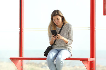 Girl checking mobile phone information in a bus stop