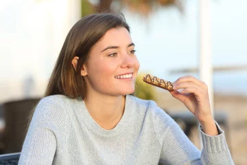 Foto op Aluminium Happy girl eating a snack in a coffee shop terrace © Antonioguillem