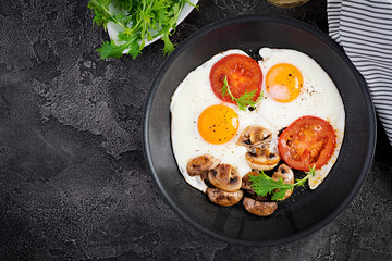 Ketogenic food. Fried egg, mushrooms and sliced tomatoes. Keto, paleo breakfast. Top view, overhead, copy space