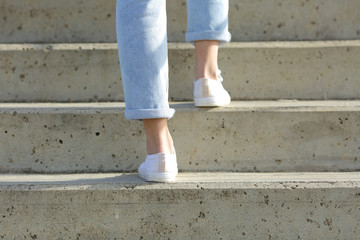 Woman legs wearing sneakers walking up stairs