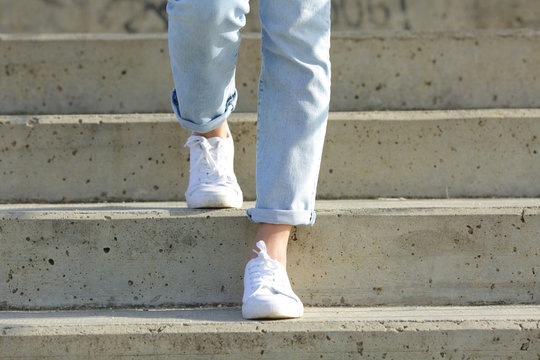 Woman legs wearing sneakers walking down stairs