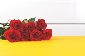 Bouquet of beautiful red rose flowers on yellow table. Close up. Copy space. 8 march, 14 february, st valentine day and women's day concept.