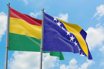 Bosnia Herzegovina and Bolivia flags waving in the wind against white cloudy blue sky together. Diplomacy concept, international relations.
