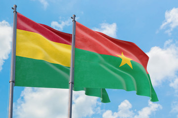 Burkina Faso and Bolivia flags waving in the wind against white cloudy blue sky together. Diplomacy concept, international relations.