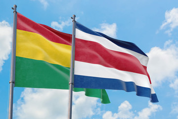 Costa Rica and Bolivia flags waving in the wind against white cloudy blue sky together. Diplomacy concept, international relations.