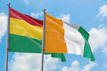 Cote D'Ivoire and Bolivia flags waving in the wind against white cloudy blue sky together. Diplomacy concept, international relations.